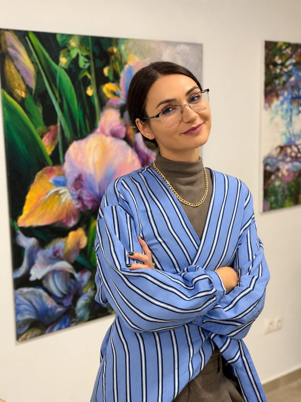 Mirela Patras in the gallery, next to her paintings